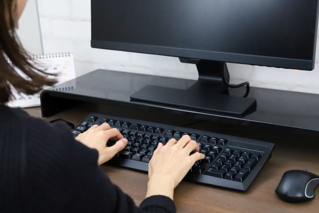 デスクトップパソコンに向かう女性の画像