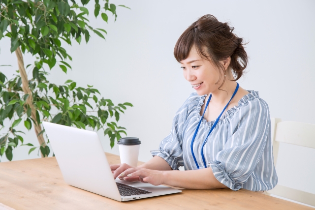 女性が笑顔でキーボードのタイピングをしている画像