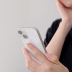 スマホを見つめながら考える女性