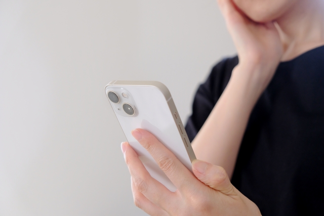 スマホを見つめながら考える女性